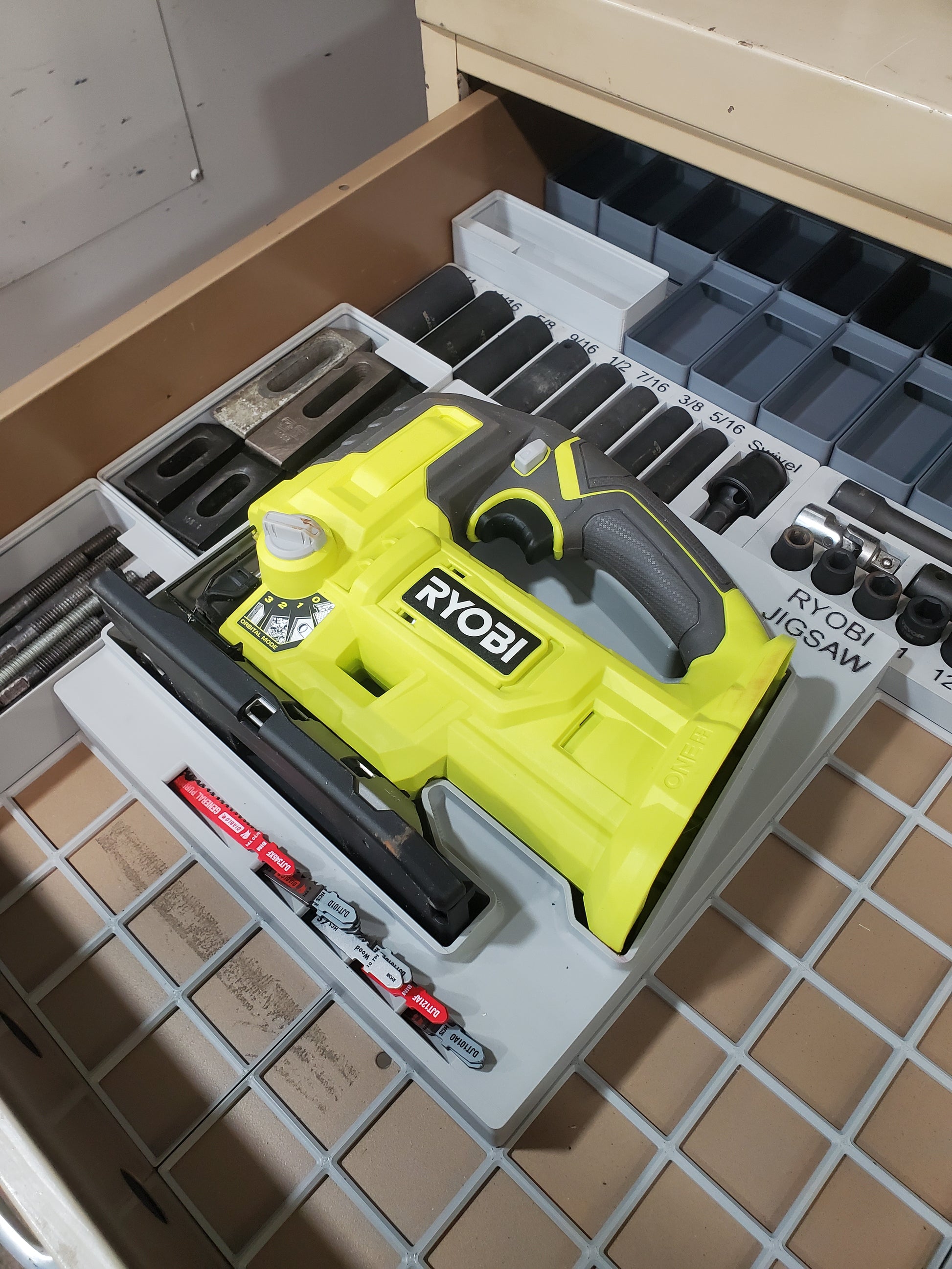 Gridfinity Ryobi reciprocating saw jigsaw module showing yellow and black Ryobi jigsaw mounted in gray gridfinity tool organizer tray, designed to store and organize jigsaw blades and accessories