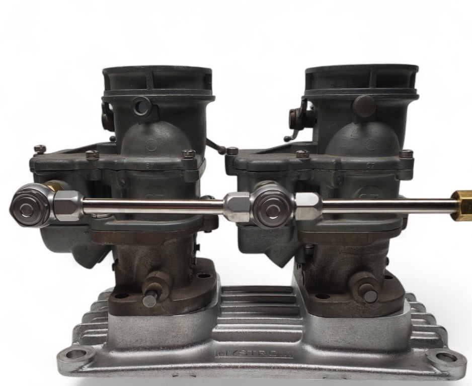 Dual Stromberg 97 carburetor assembly mounted on intake manifold, featuring compression banjo fuel fittings and polished fuel line connecting the carburetors