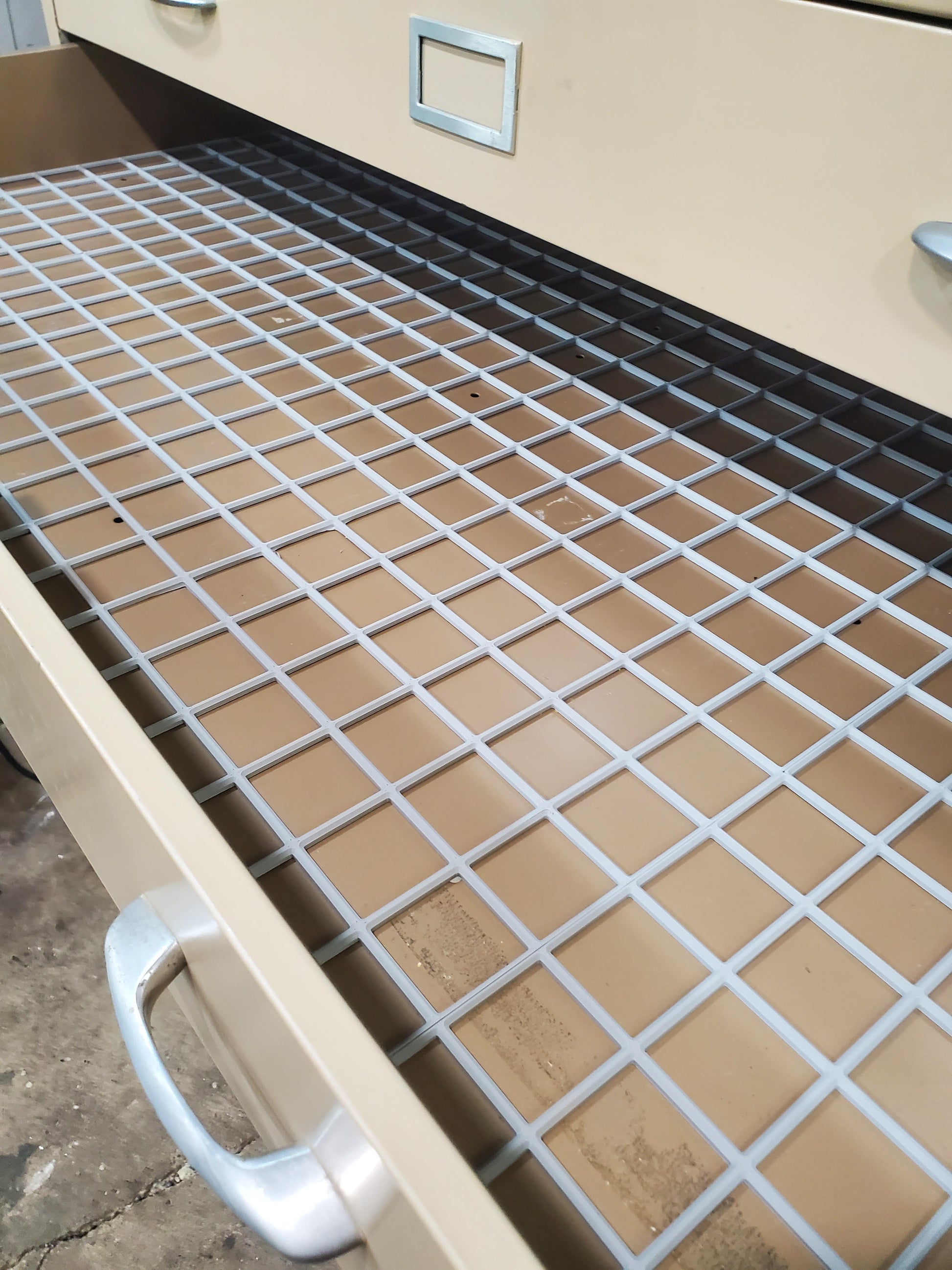 Gridfinity base grid panel installed in a drawer, showing structured square pattern for organizing tool modules and parts within the Gridfinity system