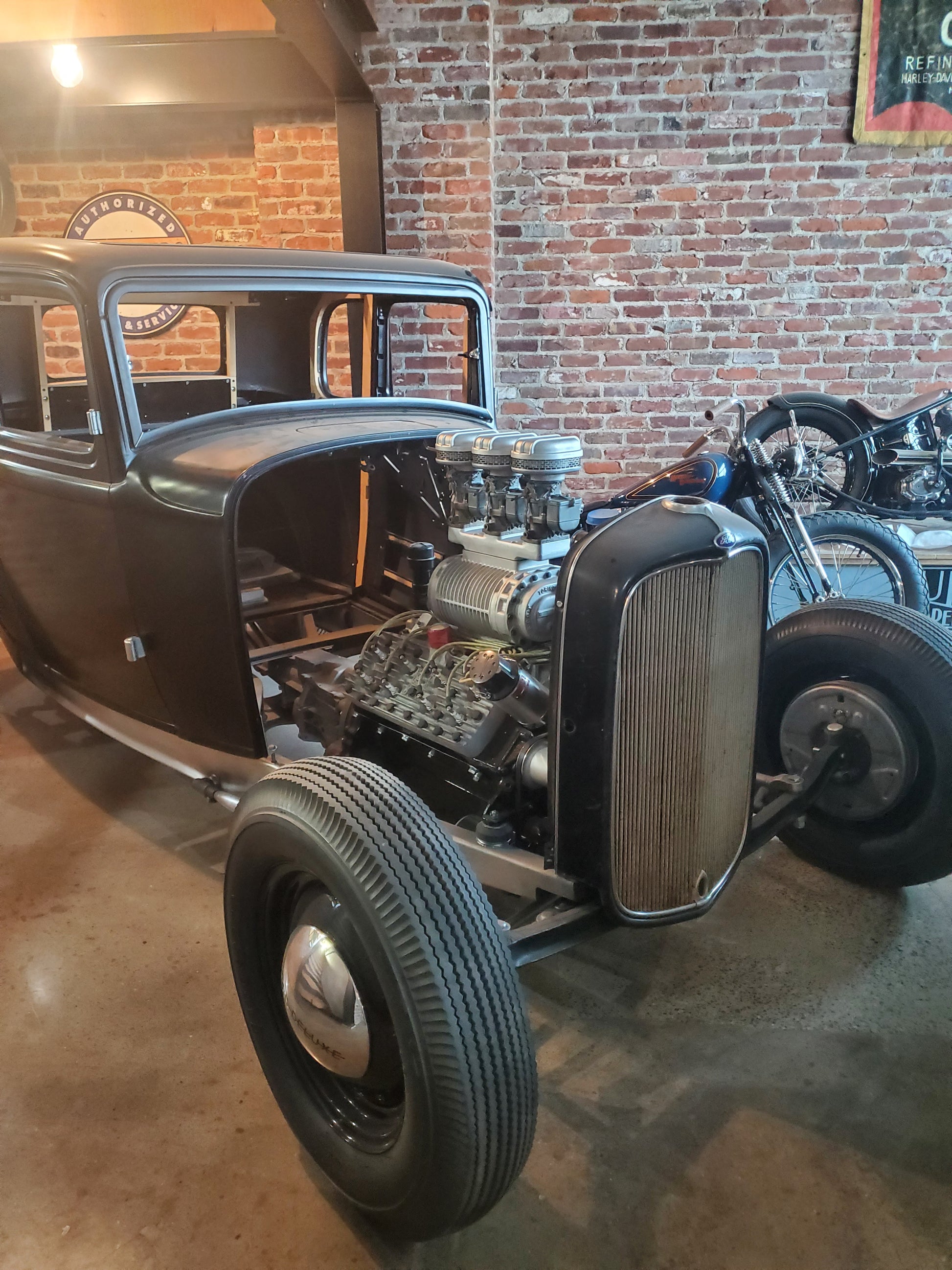 Classic hot rod project car in garage equipped with S.c.o.T. Italmechanicca 3×2 adapter and supercharged V8 engine featuring three Stromberg carburetors; car body partially assembled on polished floor